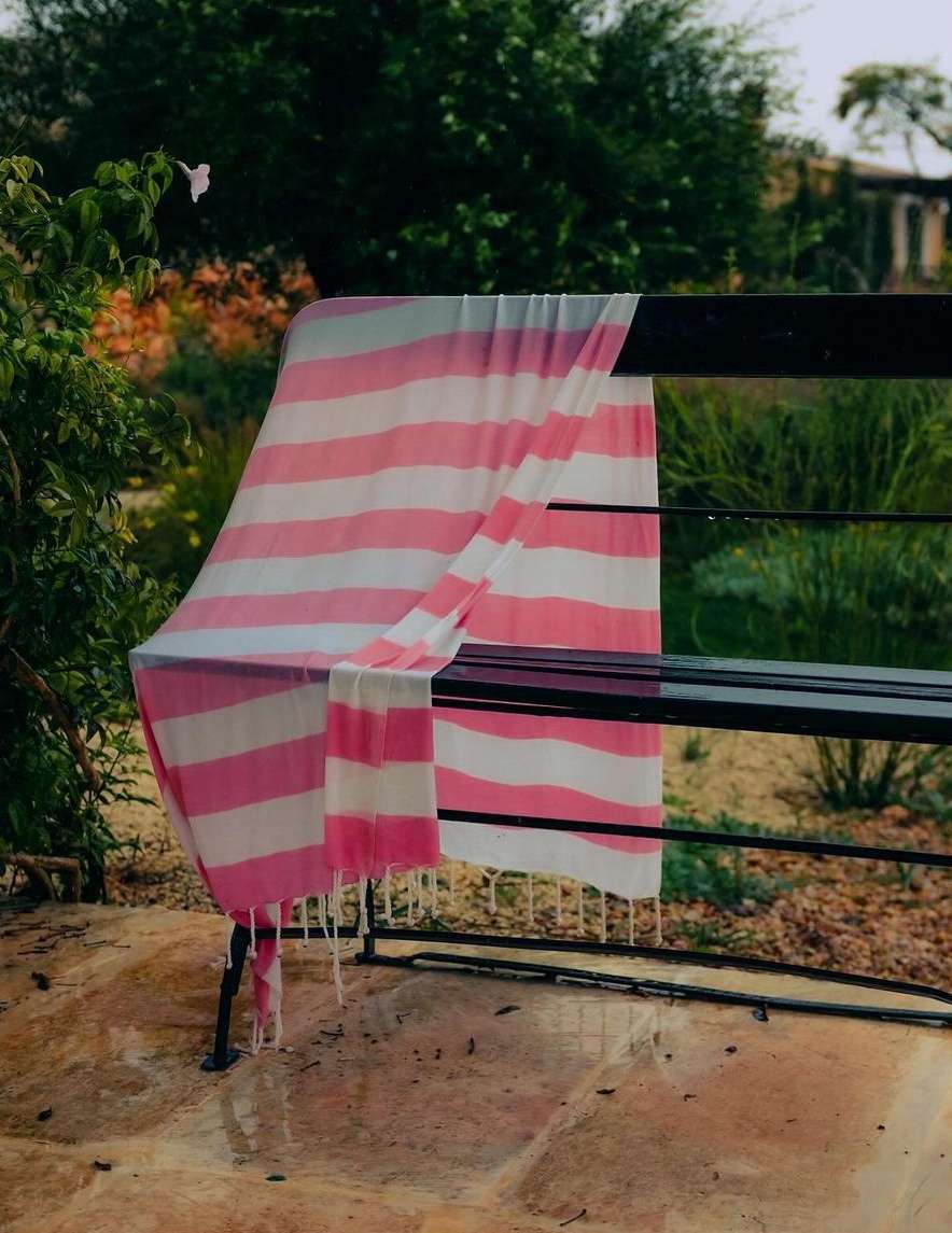 Pink and white striped throw blanket draped over a black park bench outdoors
