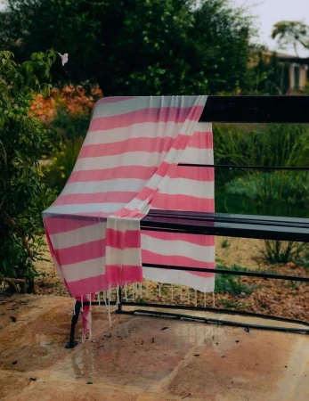 Pink and white striped throw blanket draped over a black park bench outdoors