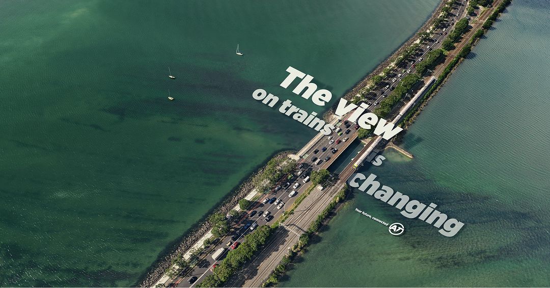 Aerial view of a bridge with car and train traffic over a green body of water, featuring sailboats and promotional text overlay.