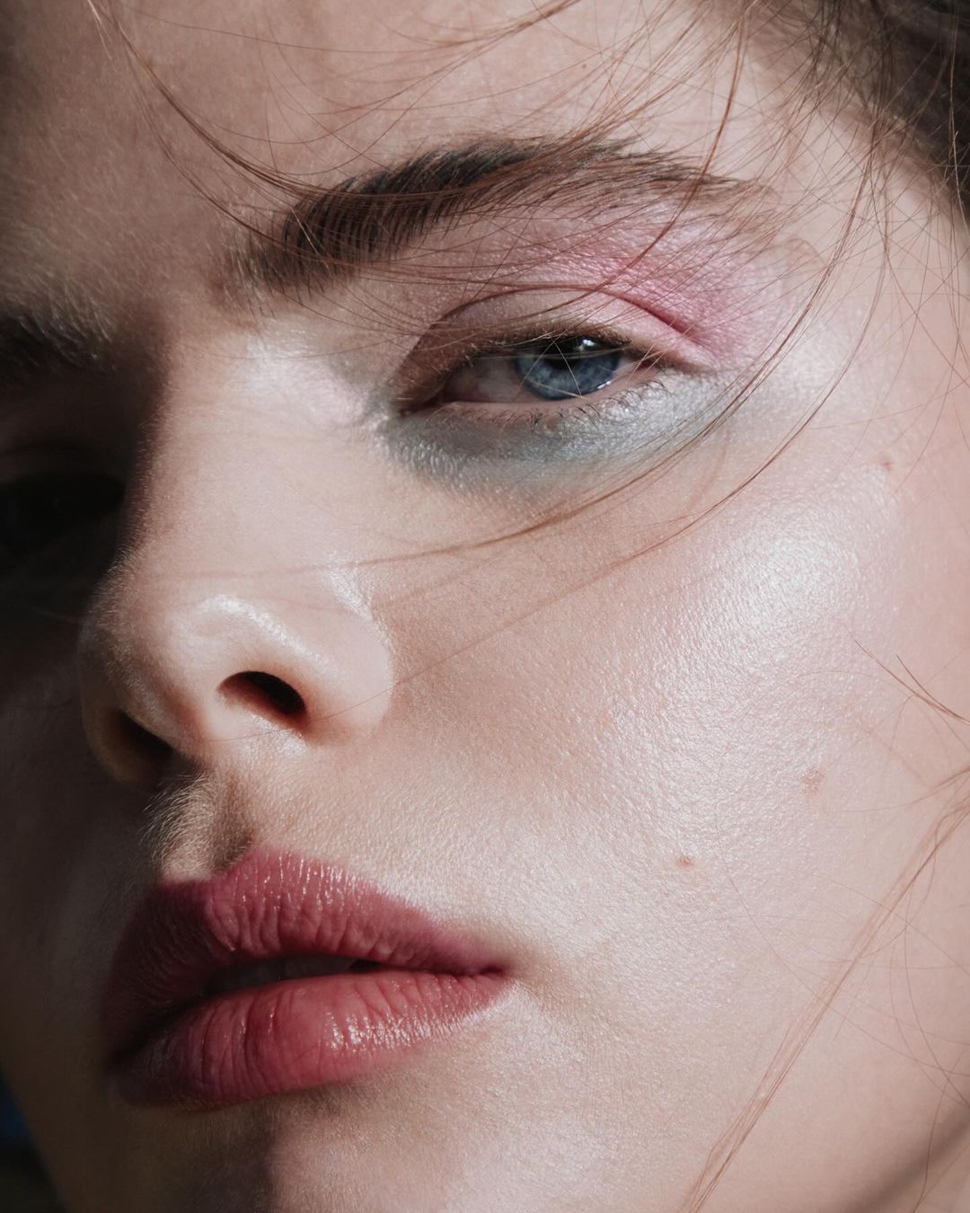 Extreme close-up portrait of a woman with blue eyes, pink and green eyeshadow, and glossy dark pink lips by Mei Tao.