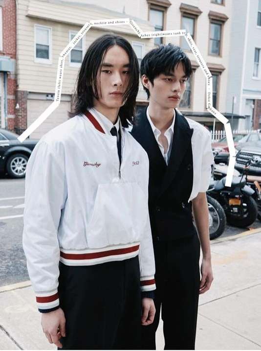 Two young adult models pose in street fashion against a city building backdrop, showcasing modern jackets and tailored vest styles.