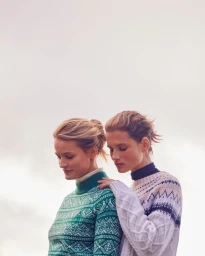 Two female models wearing patterned knit turtlenecks outdoors against an overcast sky, photographed by Mei Tao.