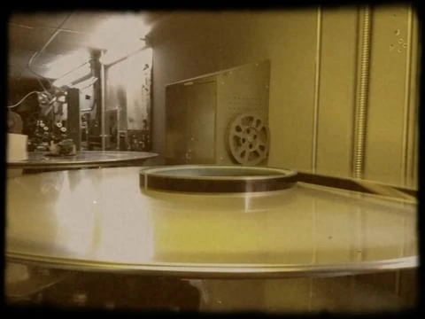 Close-up of vintage film editing equipment showing the film moving over a clear surface, bathed in warm, golden light.
