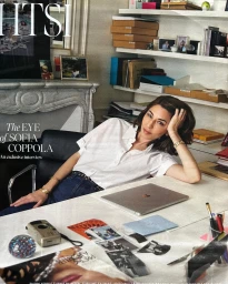 Sofia Coppola seated at a white desk in an office with shelves, photographed by Melodie Mcdaniel.