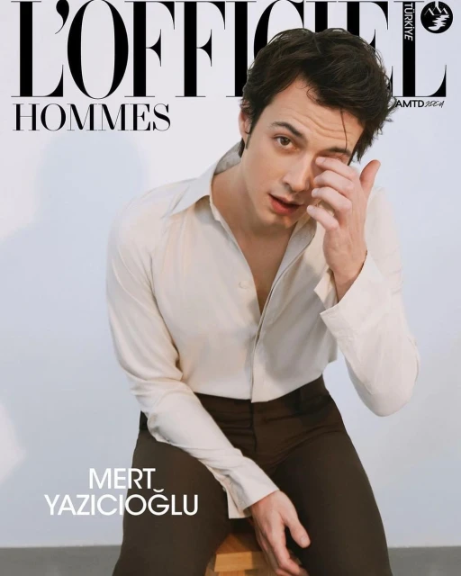 Magazine cover featuring Mert Yazicioglu in a light shirt and dark pants, seated on a wooden stool against a clean white background.