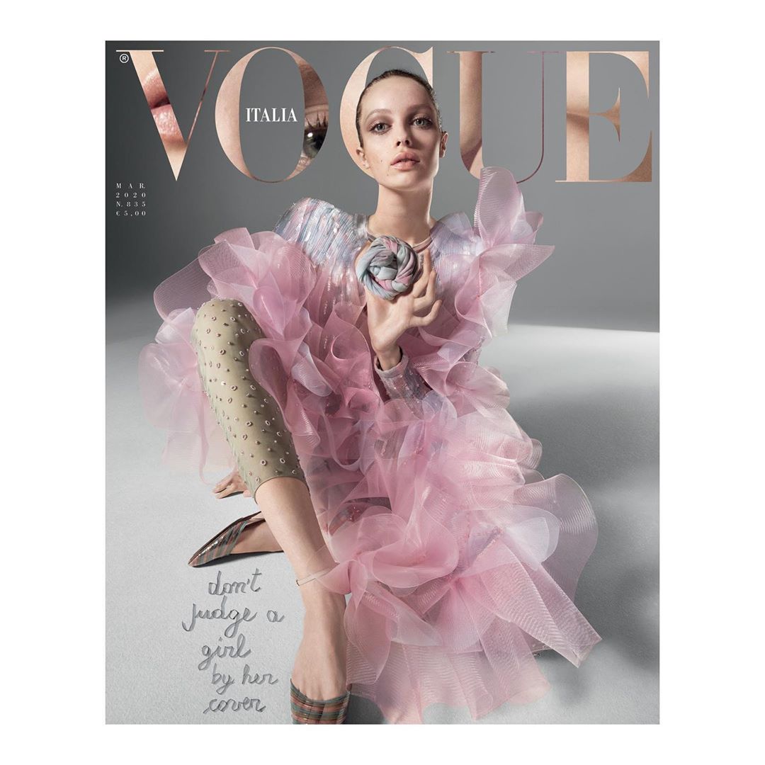 Vogue Italia cover featuring a fair-skinned model in a pink ruffled dress, seated against a gray background with visible text overlay.
