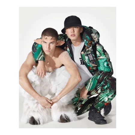 Two men pose in a studio: one is wearing a green patterned jacket and a black hat, the other is wearing a faun costume.
