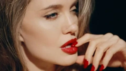 Close-up portrait of a woman with red lips and matching red nails photographed by Mert Alas and Marcus Piggott.