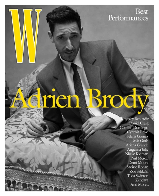 Magazine cover of Adrien Brody wearing suit and tie, reclining on patterned bedspread with magazine text and titles in yellow and white.