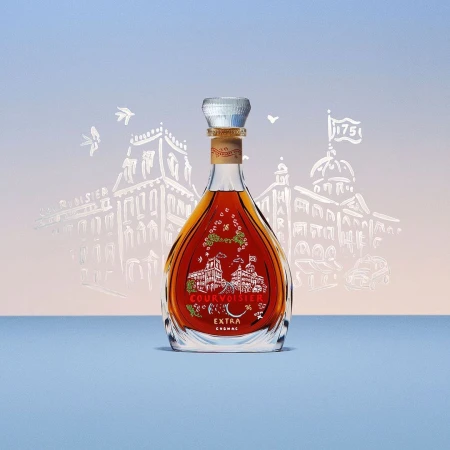 Studio shot of a Courvoisier Cognac bottle featuring a silver cap, building drawings, and light blue background, perfect for spirits and beverages.