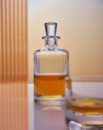 Crystal decanter with amber liquid and glass on a reflective surface against an orange gradient background, showcasing glassware elegance.