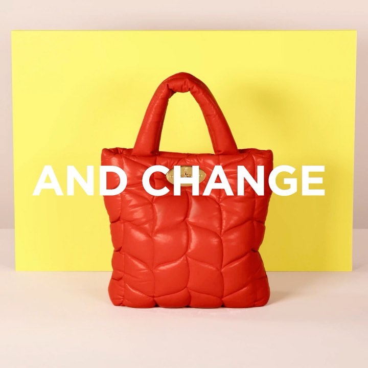 Studio shot of a quilted red tote bag with handles against a yellow and light pink backdrop, illuminated by studio lighting.