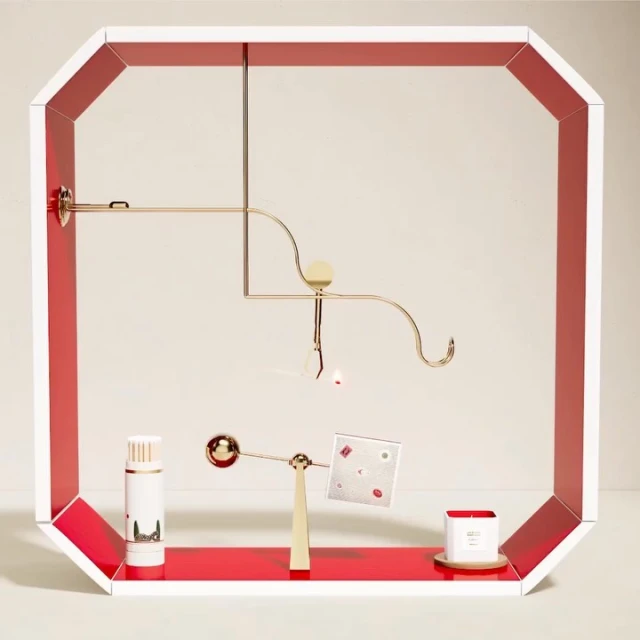 Abstract product display featuring cylindrical bottles, candle, and geometric shapes in a white and red frame against a neutral backdrop.