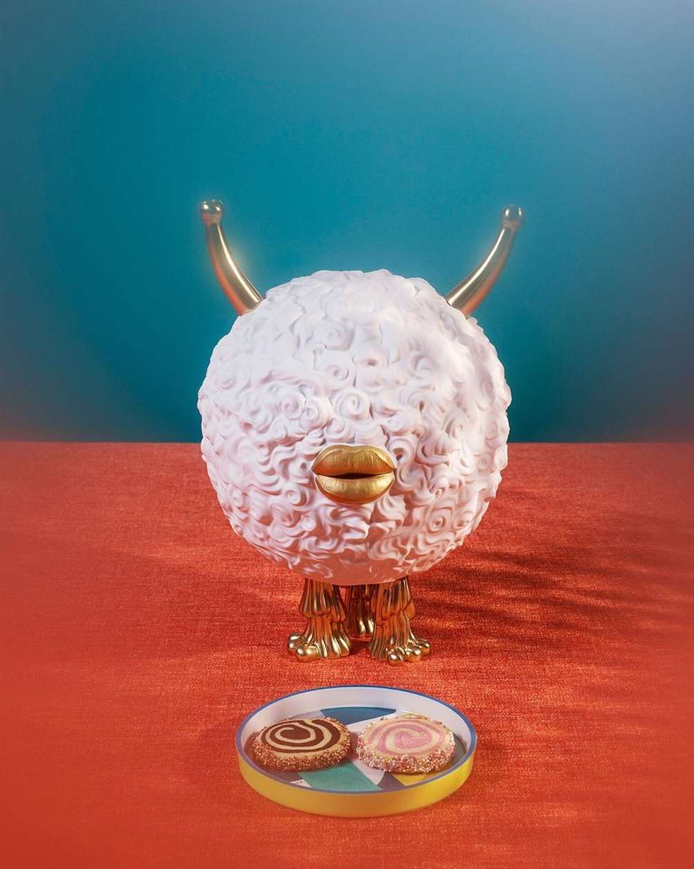 A surreal, fantastical image featuring a white, round, animal-like creature with golden horns and lips standing above a plate of cookies.