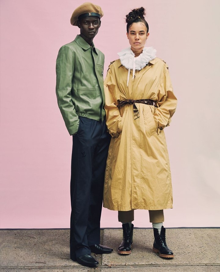 Two fashion models in stylish outfits pose in front of a light pink backdrop and concrete floor. A light-skinned female and a dark-skinned male.