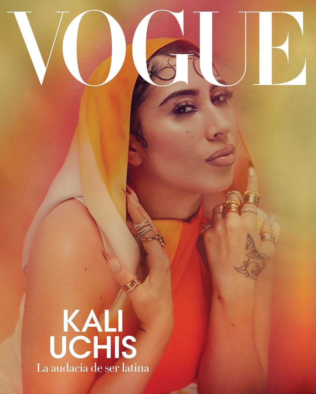 Vogue magazine cover featuring Kali Uchis, showcasing a close-up of her face adorned with jewelry and a head covering in warm tones.