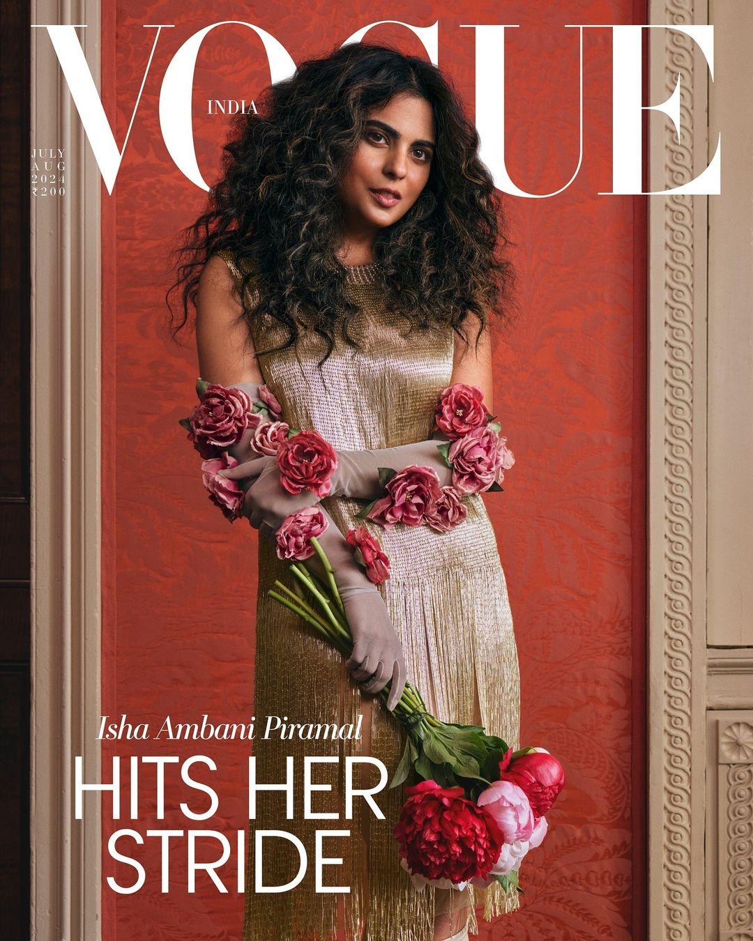Vogue cover featuring woman with curly hair in gold dress adorned with pink roses, holding a bouquet of roses, against a textured orange background.