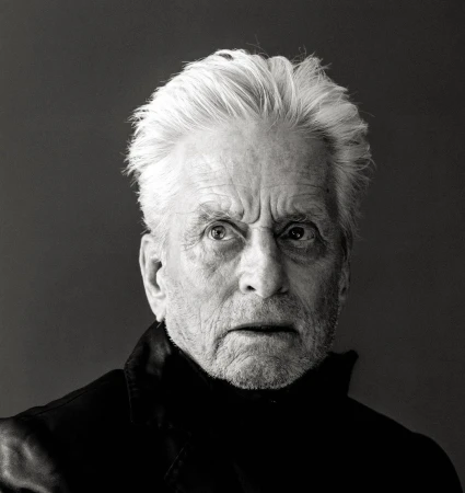 Black and white portrait of an elderly adult male with gray hair wearing a dark turtleneck sweater against a grey background.