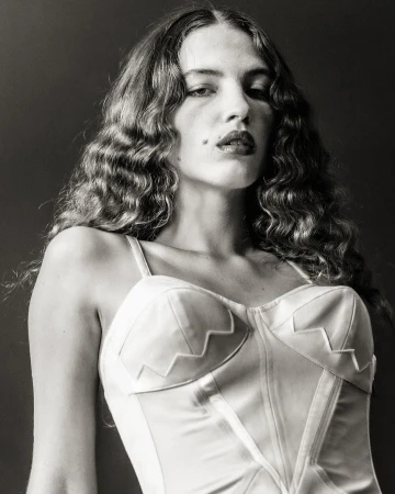 Portrait of a woman with long wavy hair wearing a white corset top, photographed by Michael Avedon.