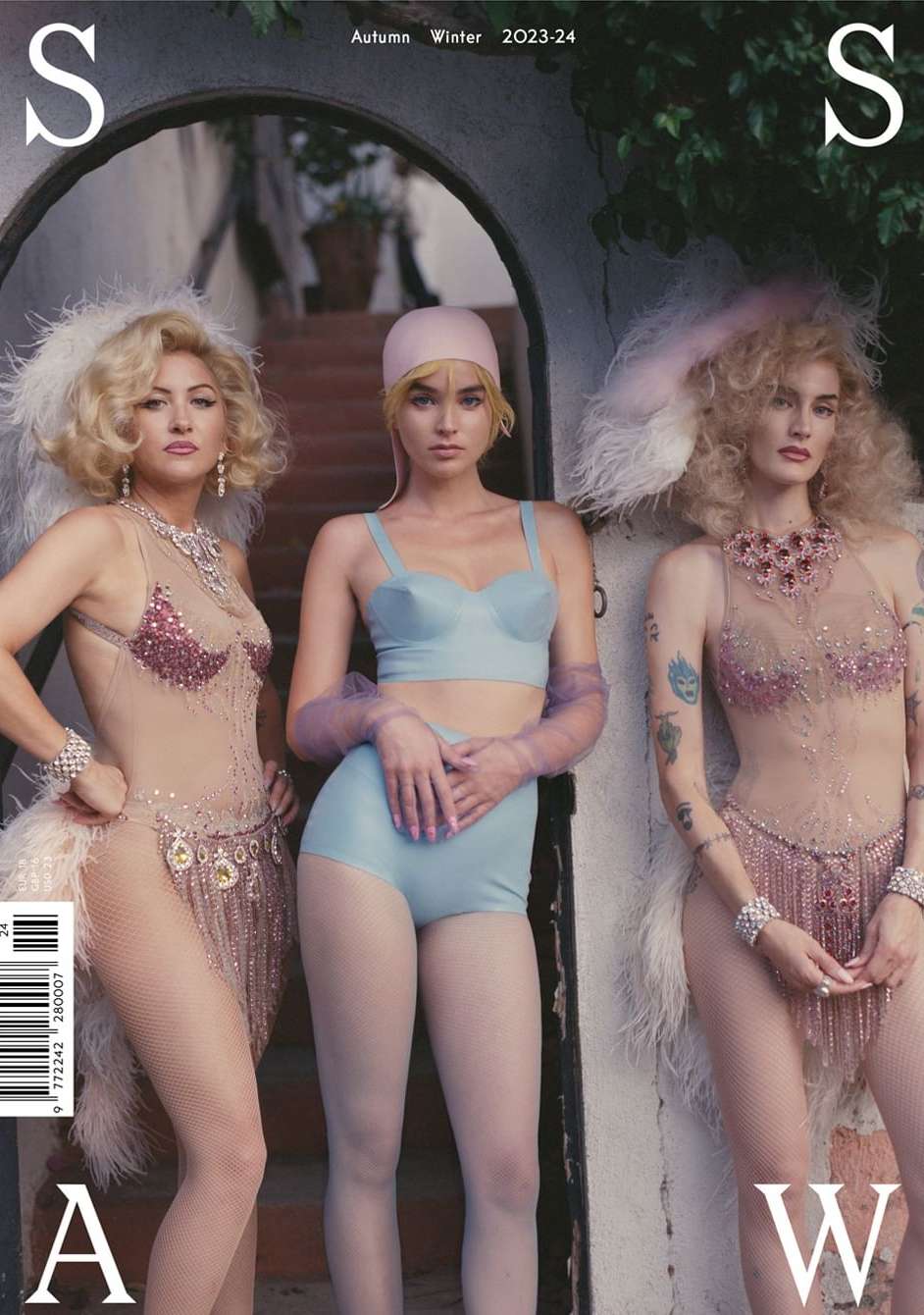 Magazine cover featuring three women in vintage-inspired lingerie and elaborate hairstyles, posing in front of an arched doorway.