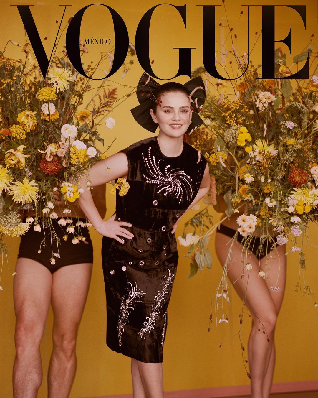 Vogue Mexico cover featuring Selena Gomez in an embellished black dress, surrounded by floral arrangements, against a yellow backdrop.
