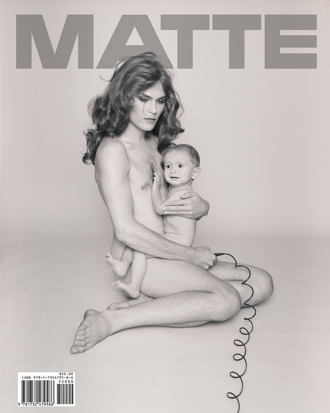 Monochrome magazine cover featuring an androgynous adult holding a baby and seated with a coiled telephone cord.