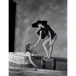 Black and white portrait of a woman standing on a stool touching a man in a bathtub by Michael Bailey-gates.