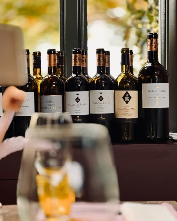 Several wine bottles standing on a dark shelf with an empty wine glass blurred in the foreground
