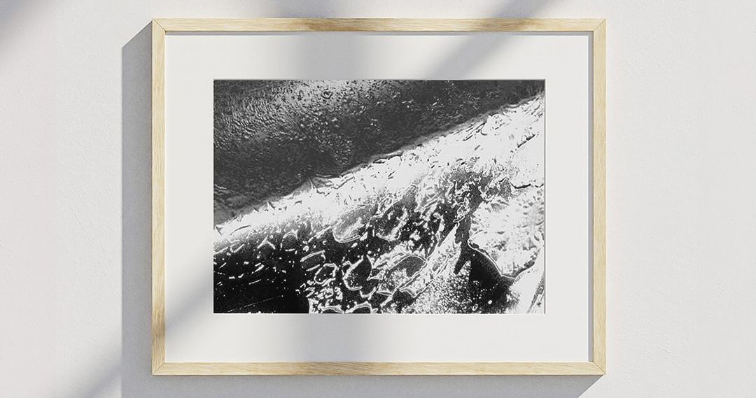 Framed black and white abstract photograph hanging on white wall, offering a minimalist aesthetic with a contemporary touch.