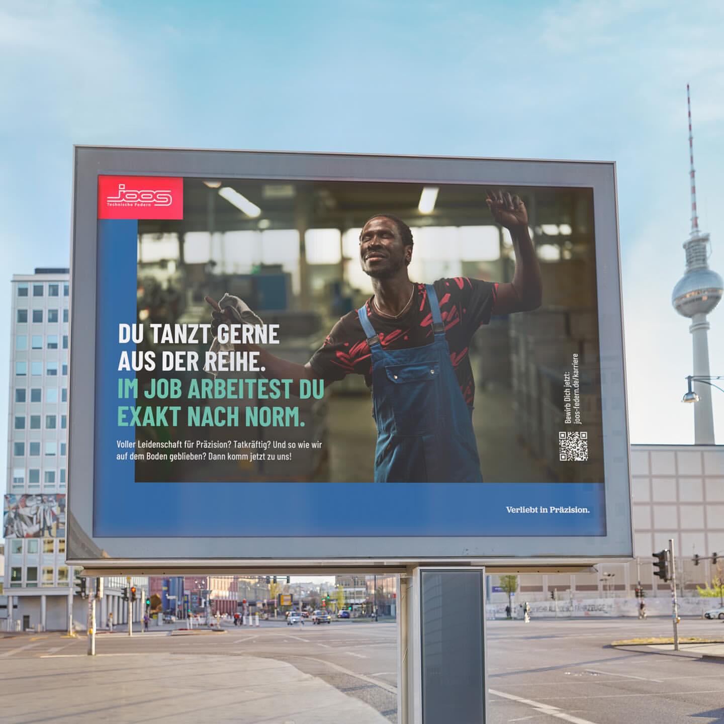 Billboard in an urban setting features an African American man in overalls. A text overlay in German advertises employment opportunities.