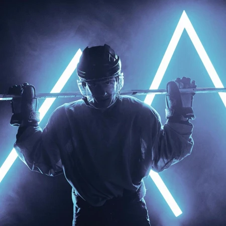 Hockey player in helmet holds stick over shoulders, portrait against graphic neon triangle, blue and black tones, dramatic lighting.