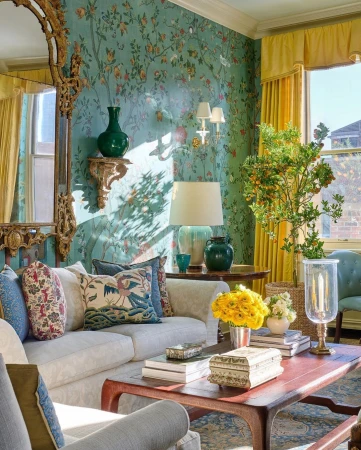 Cozy and elegant living room interior with patterned wallpaper, sofa, ornate mirror, and natural light from window.