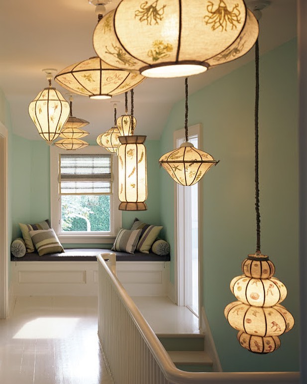 Hallway with decorative hanging lights, white walls, and a window seat creating a bright, inviting, and stylish home interior.