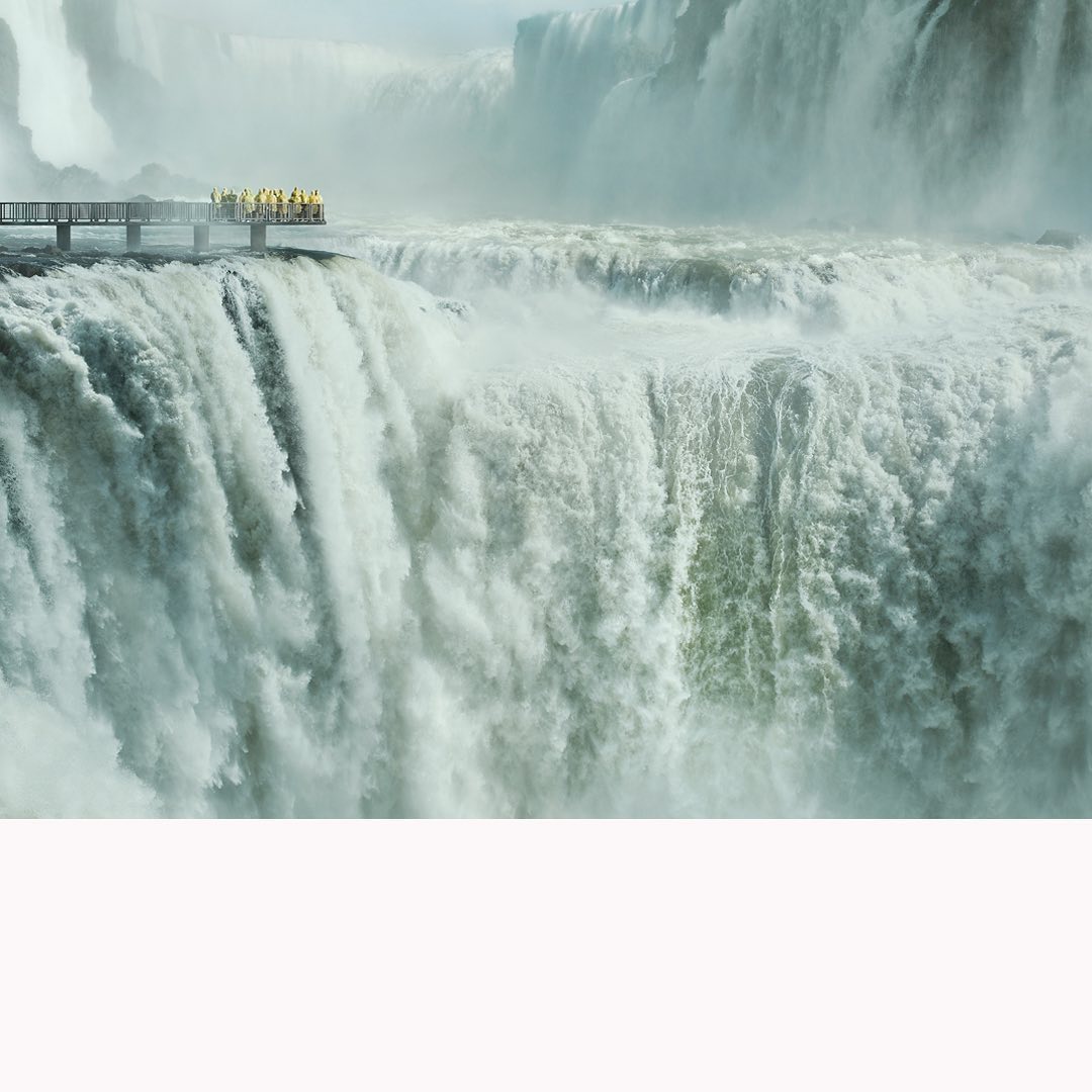 Waterfall landscape featuring a viewing platform with people, showcasing natural beauty and a tourist attraction.