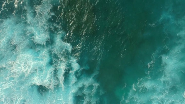 Aerial view of ocean with turquoise water and foamy waves creating a mesmerizing pattern, showcasing nature's power and beauty.