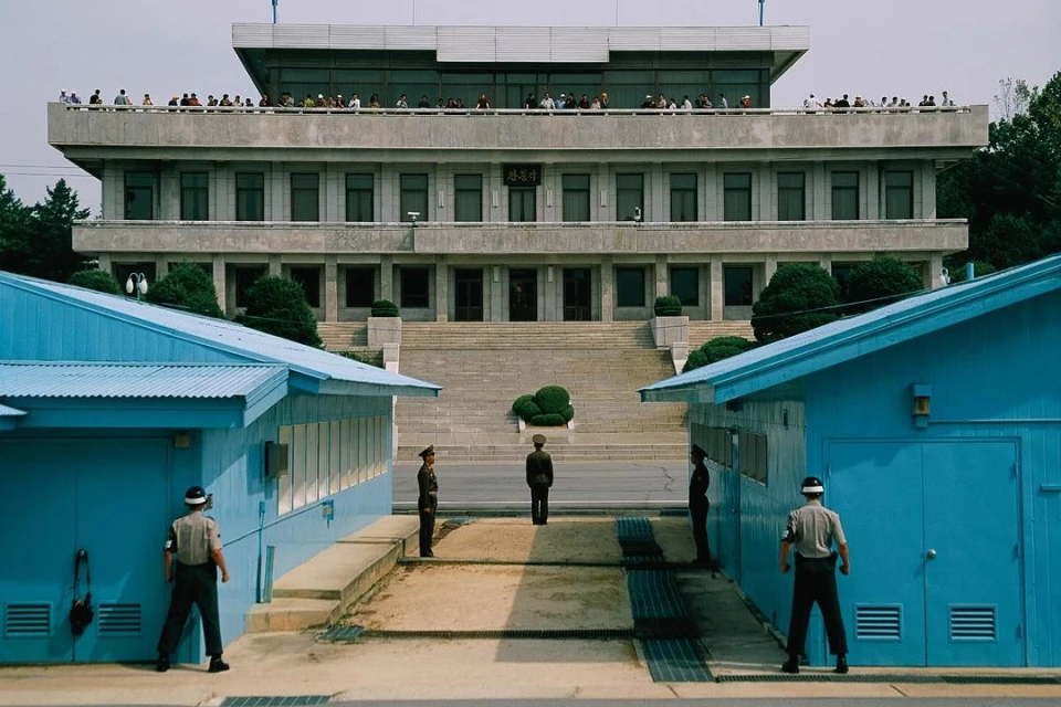 Demilitarized Zone (DMZ) with North Korean soldiers guarding border building with South Korean soldiers facing them across divide.