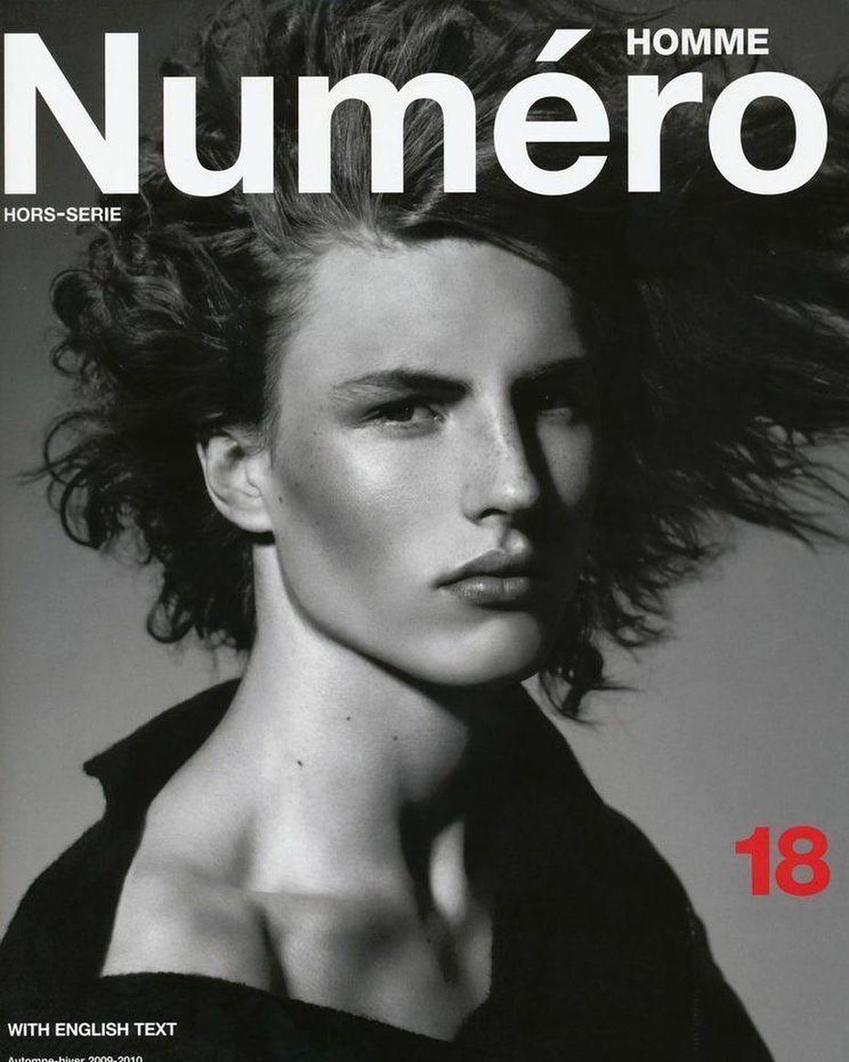 Magazine cover featuring a close-up portrait of a model with tousled hair against a grey background, with bold white and red text.