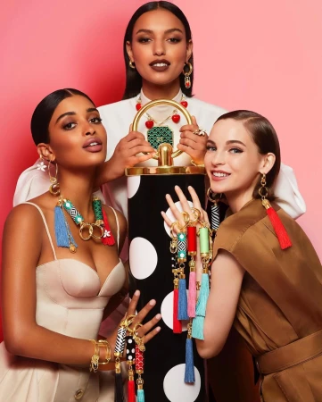 Three female models posing together showcasing colourful tassels and jewellery with a polka-dot pillar in a studio portrait