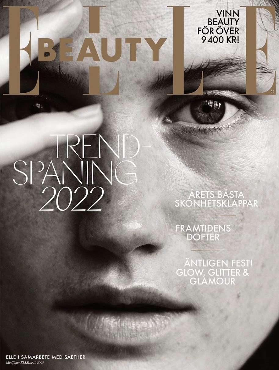 Elle Beauty magazine cover featuring a close-up portrait of a fair-skinned adult woman with her hand near her face, in black and white.