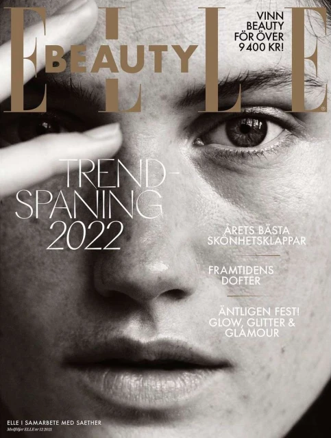 Elle Beauty magazine cover featuring a close-up portrait of a fair-skinned adult woman with her hand near her face, in black and white.