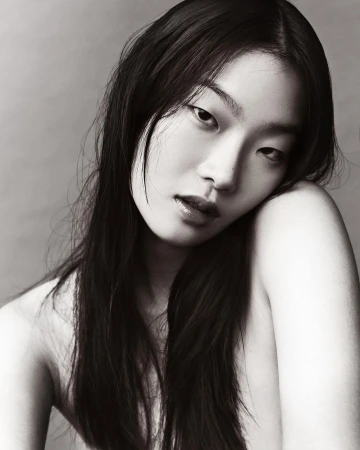 Close-up portrait of an East Asian woman with long dark hair posing against a neutral grey studio background by Mikael Schulz.