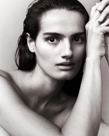 Close up portrait of a woman with wet hair posing with hands pressed against her cheek by Mikael Schulz