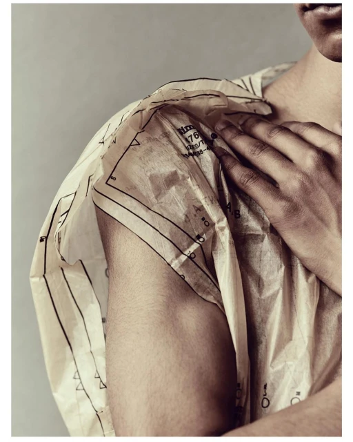 Close-up of a fair-skinned adult wearing a white garment with dark line patterns, showcasing fashion or textile design against a gray background.