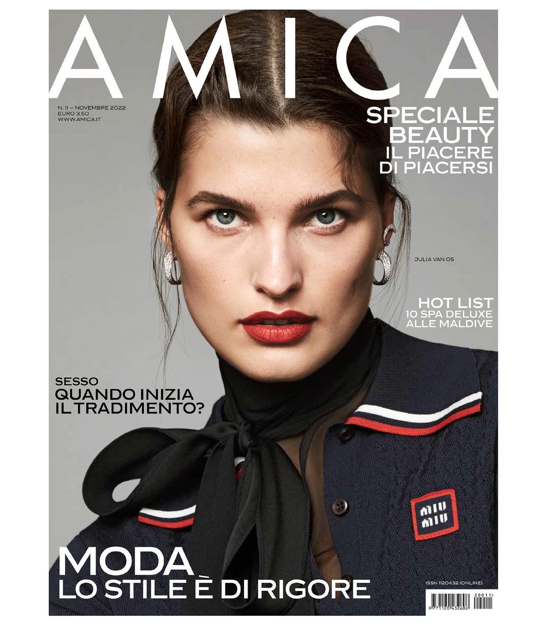Magazine cover featuring a close-up portrait of a model with red lipstick, wearing a dark jacket and scarf, on a neutral background.
