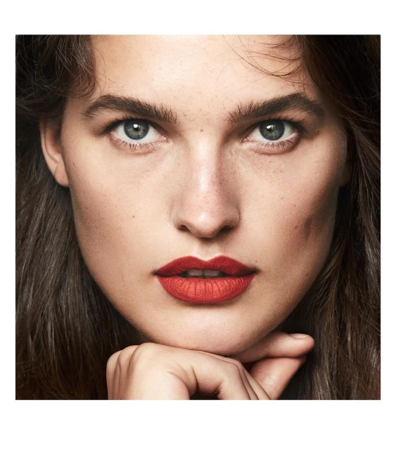 Close-up of a woman with fair skin, red lipstick, and dark brown hair. Portrait shot with soft lighting, emphasizing her facial features.