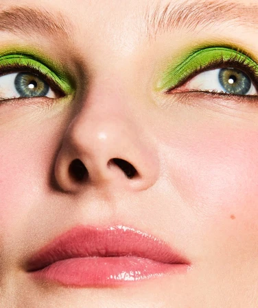 Extreme close up beauty portrait of a woman with vibrant green eyeshadow and glossy pink lips photographed by Mikael Schulz.