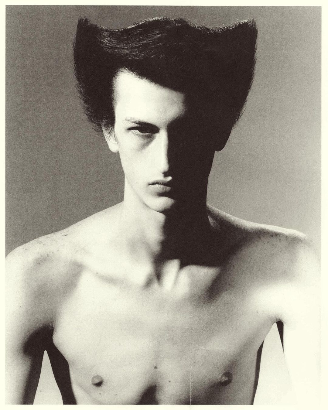 Portrait of a man with stylized flared dark hair and dramatic shadows by photographer Mikael Schulz