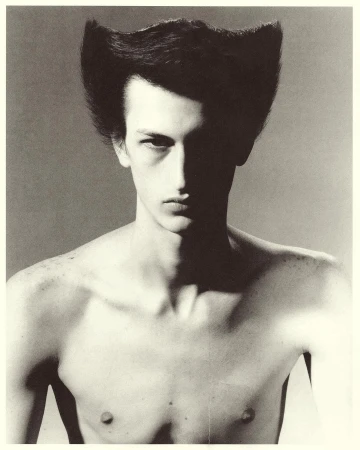 Portrait of a man with stylized flared dark hair and dramatic shadows by photographer Mikael Schulz
