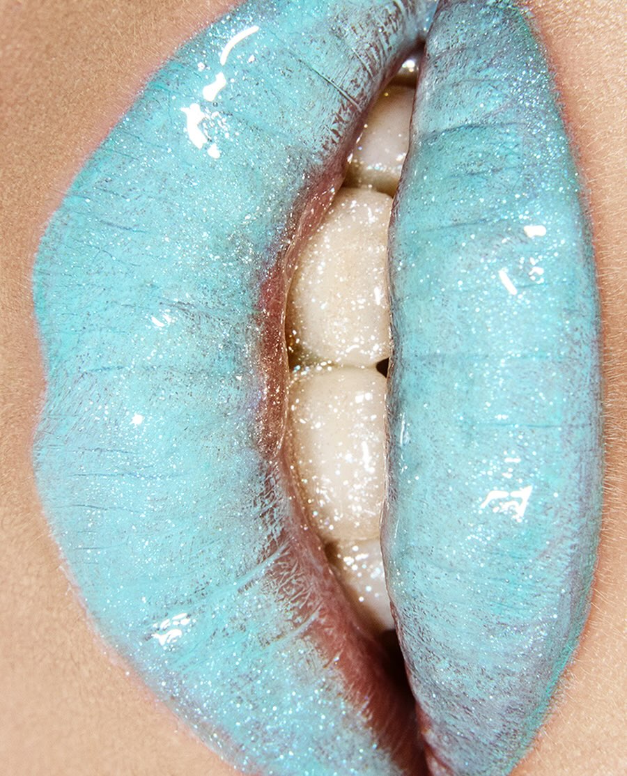Close-up studio shot of a woman's mouth with blue lipstick and visible teeth, showcasing beauty and cosmetic enhancement.
