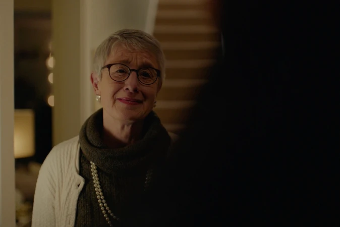 Elderly woman with short grey hair and glasses wearing a turtleneck sweater and pearl necklace by Mike Seehagel